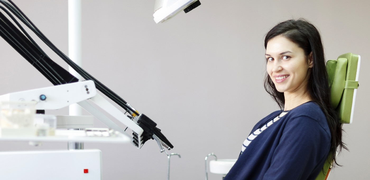 Woman in blue blouse smiling in dental chair