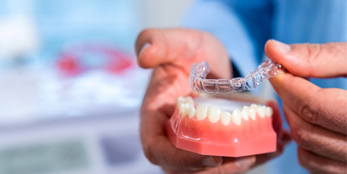 Dentist putting clear aligner on model of teeth