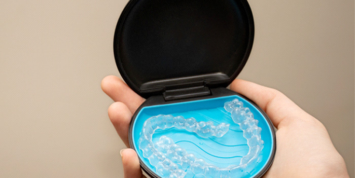 Patient holding clear aligners in black and blue case