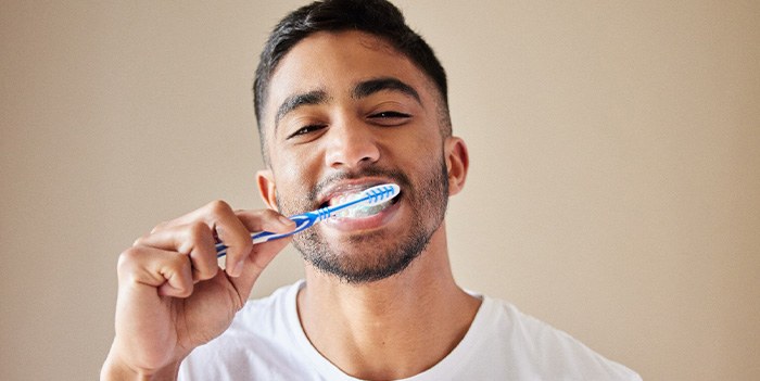 Man smiling while brushing his teeth