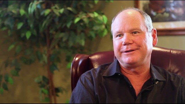 Doctor Hutto sitting on a leather chair with a fern in the background