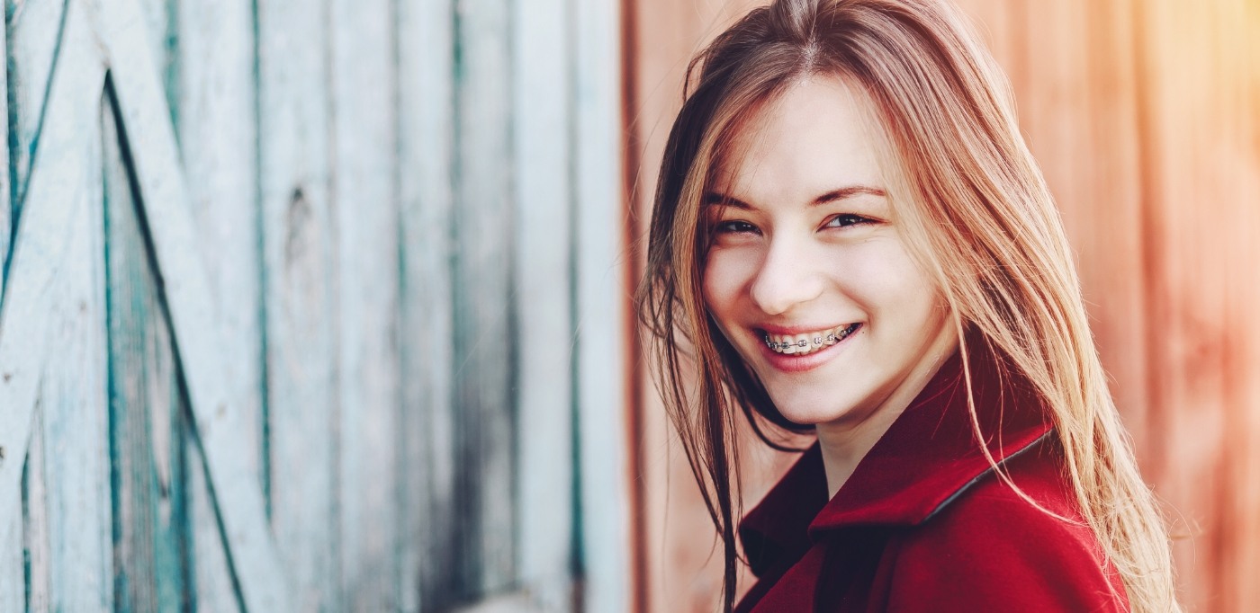 Young woman in red coat smiling with braces